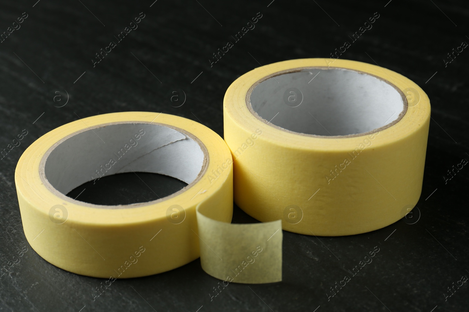 Photo of Rolls of masking tape on black table, closeup