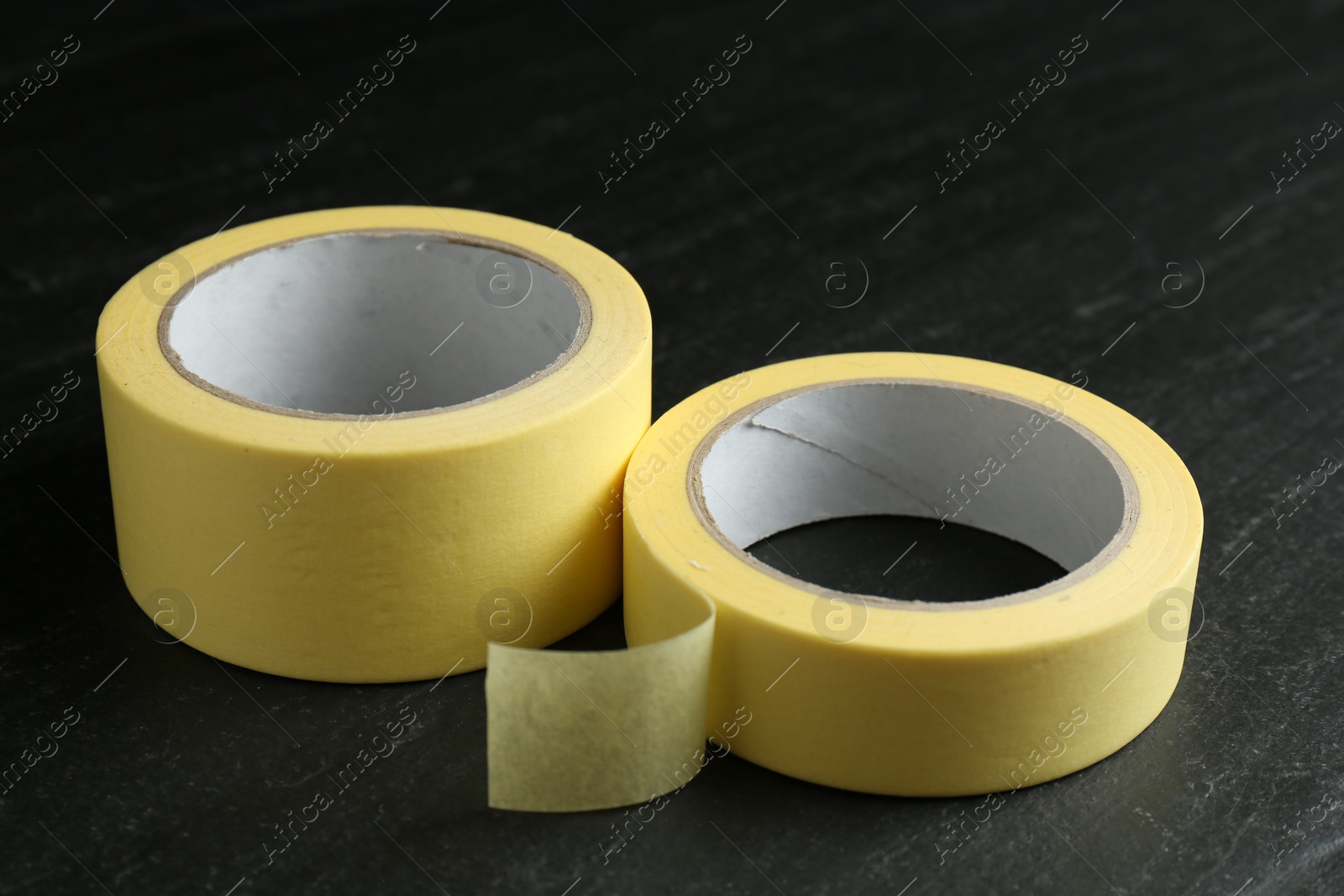 Photo of Rolls of masking tape on black table, closeup