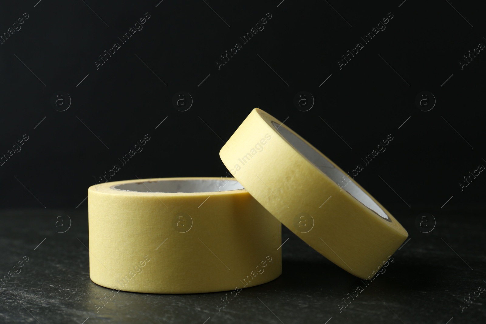 Photo of Rolls of masking tape on black table, closeup