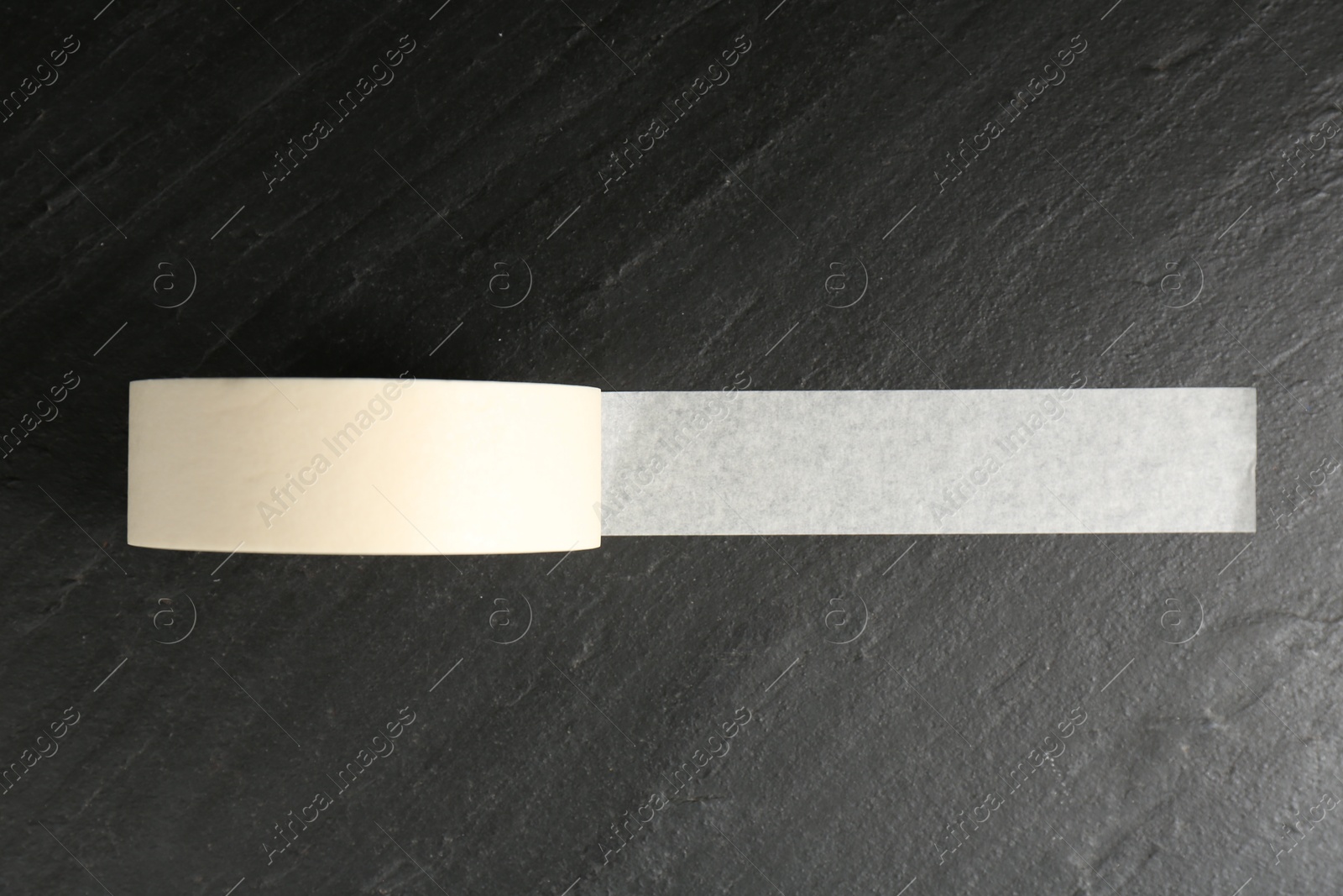 Photo of Roll of masking tape on black table, top view