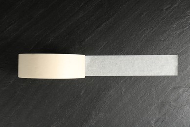 Photo of Roll of masking tape on black table, top view