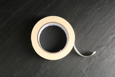 Photo of Roll of masking tape on black table, top view