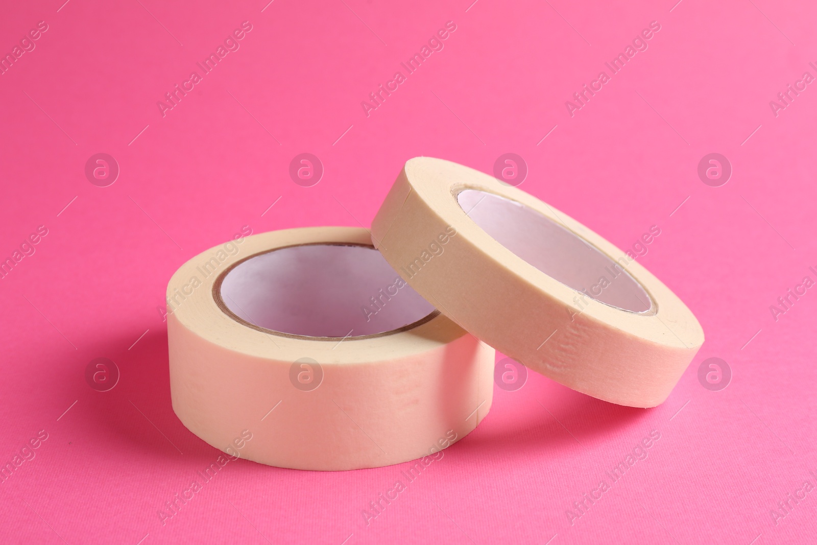 Photo of Two masking tapes on pink background, closeup