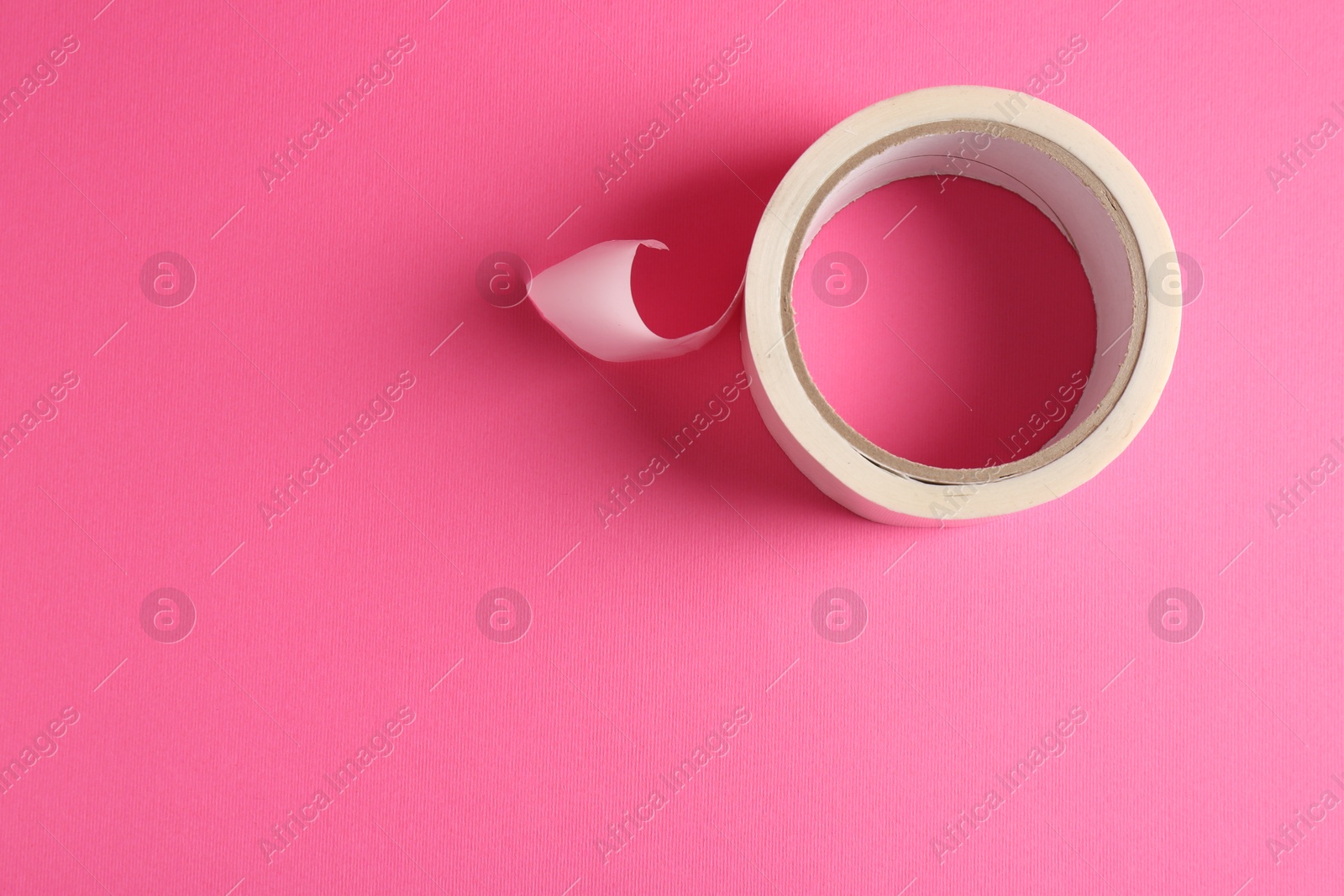 Photo of One masking tape on pink background, top view. Space for text