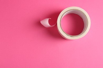 Photo of One masking tape on pink background, top view. Space for text