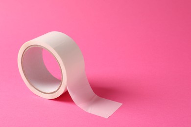 One masking tape on pink background, closeup. Space for text