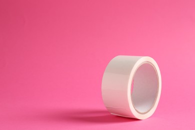 One masking tape on pink background, closeup. Space for text