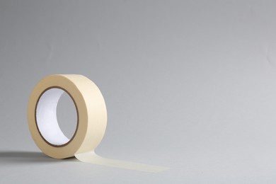 Photo of One masking tape on grey background, closeup. Space for text