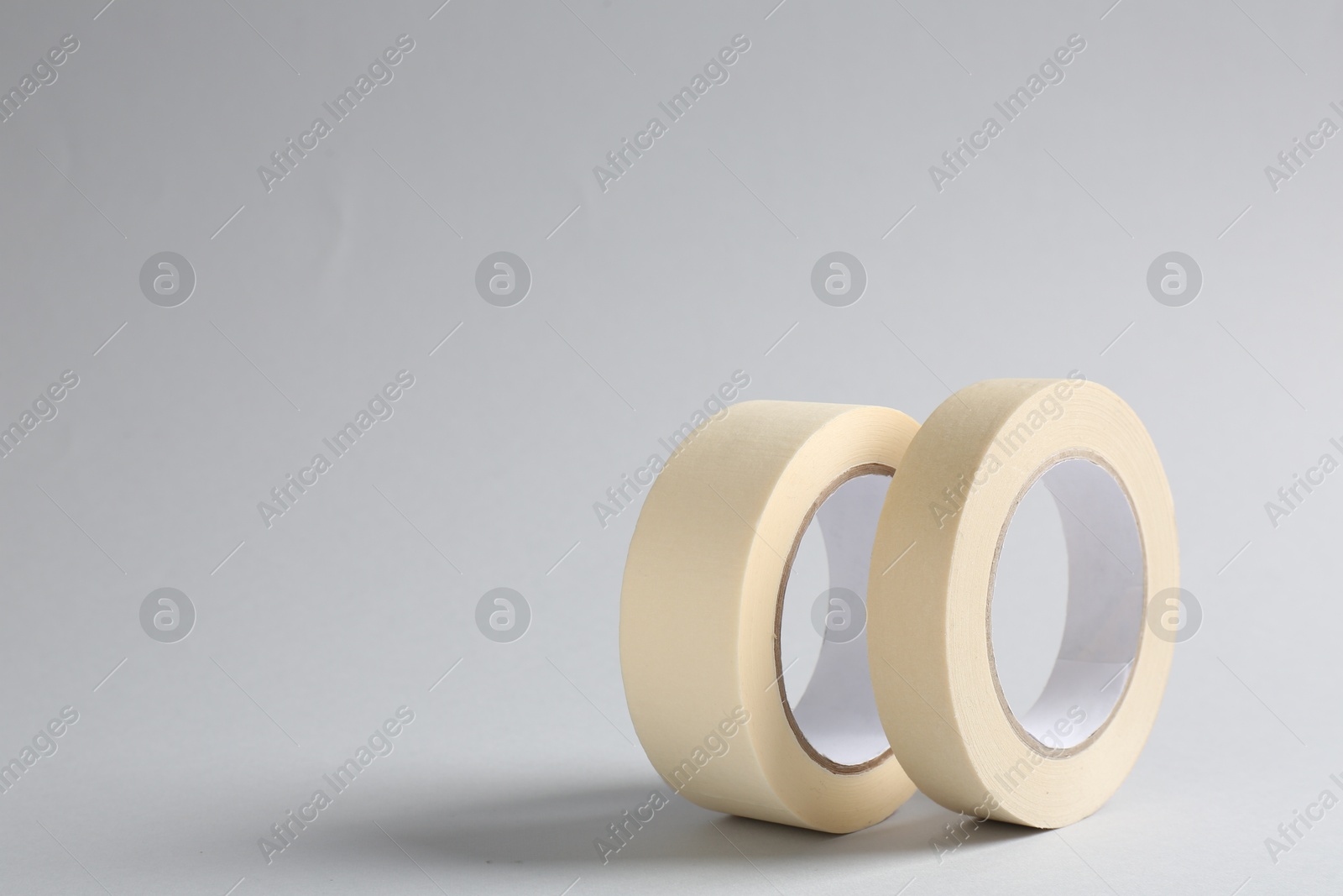 Photo of Two masking tapes on grey background, closeup. Space for text