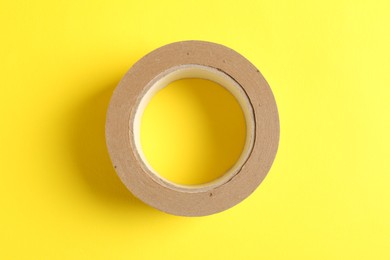 Photo of One masking tape on yellow background, top view