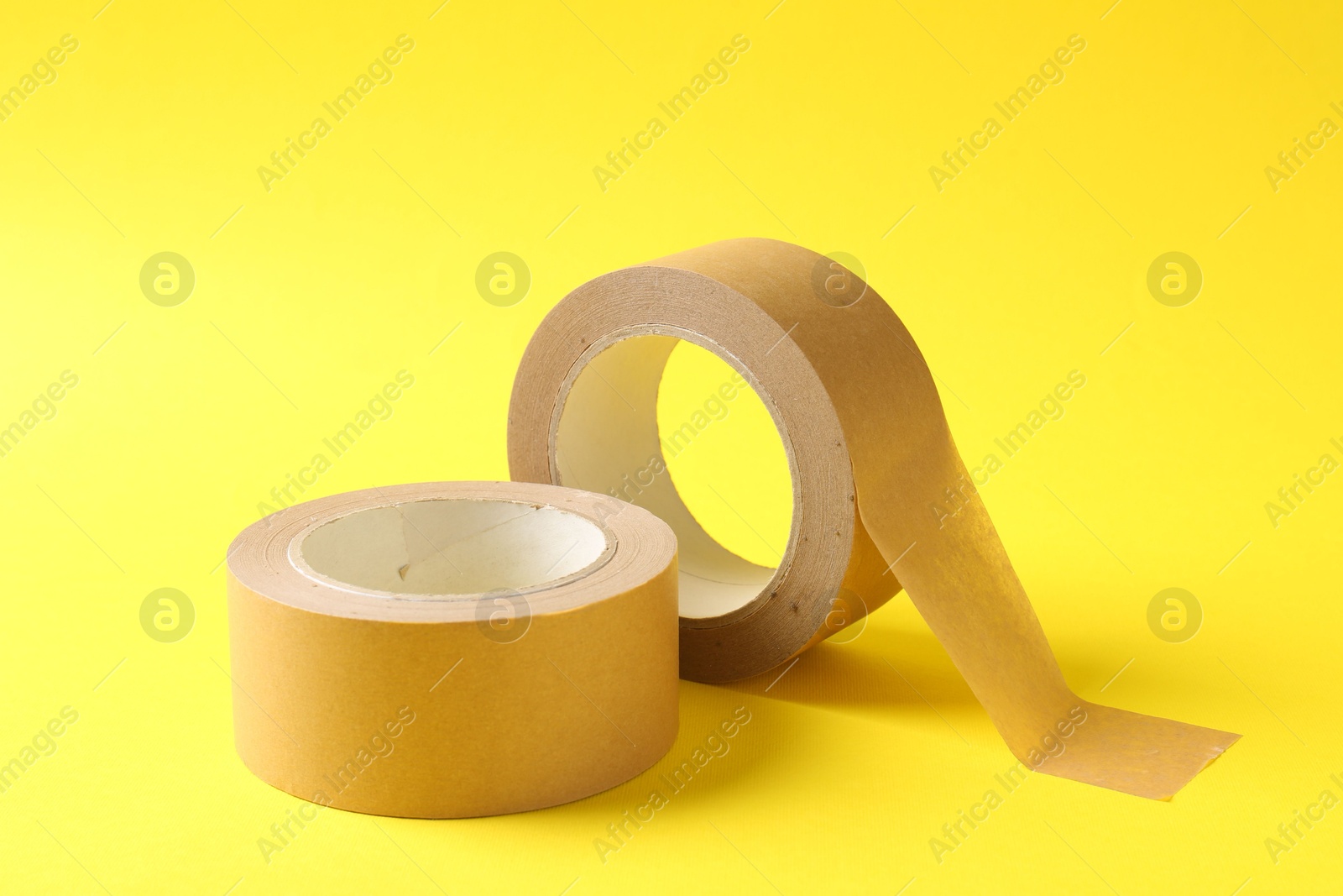 Photo of Two masking tapes on yellow background, closeup