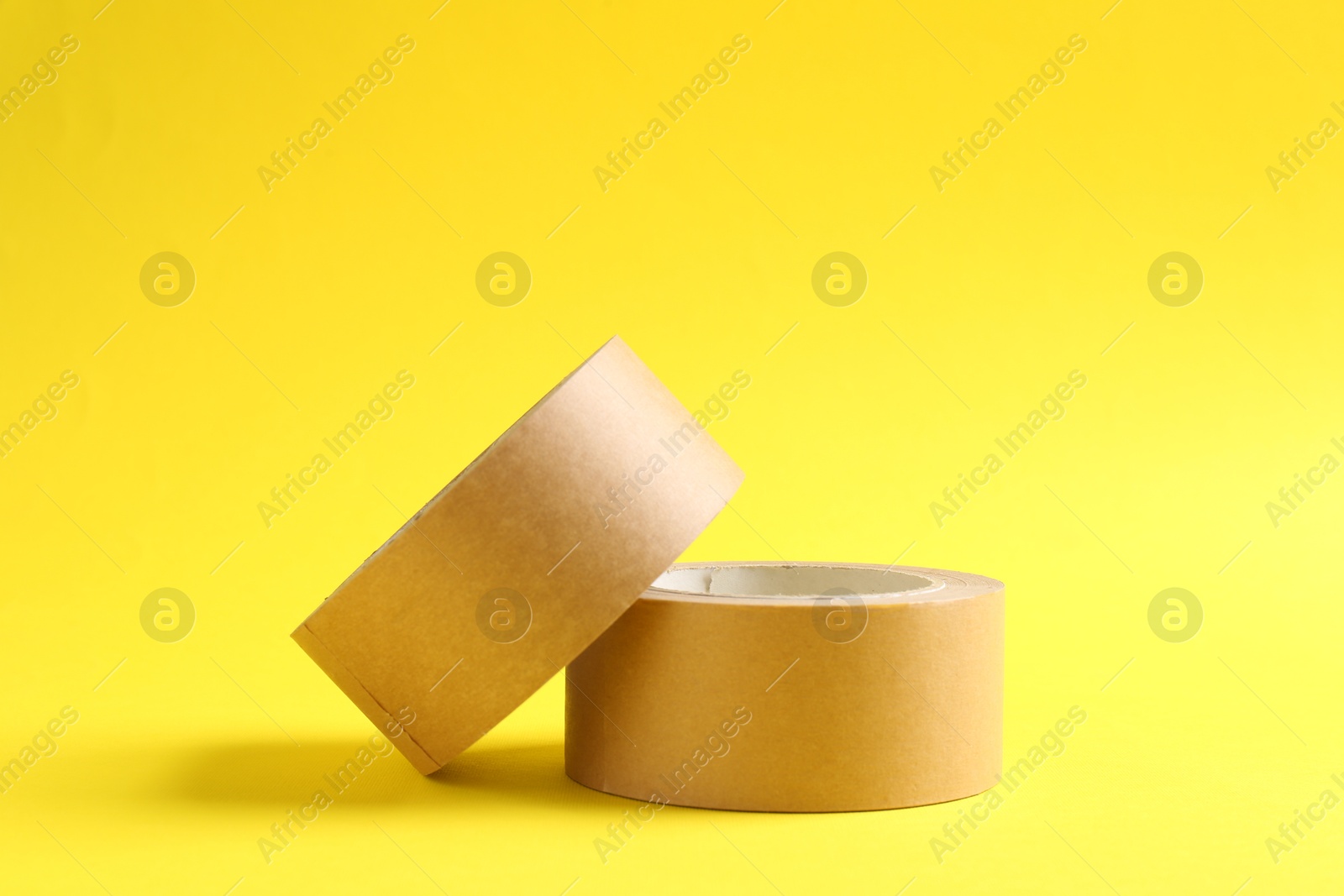 Photo of Two masking tapes on yellow background, closeup