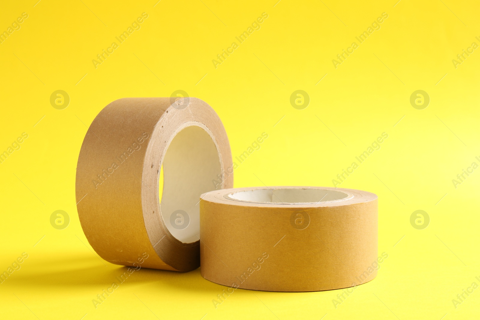 Photo of Two masking tapes on yellow background, closeup