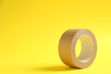 One masking tape on yellow background, closeup. Space for text