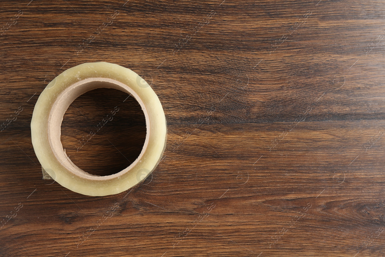 Photo of One adhesive tape on wooden table, top view. Space for text