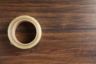 One adhesive tape on wooden table, top view. Space for text