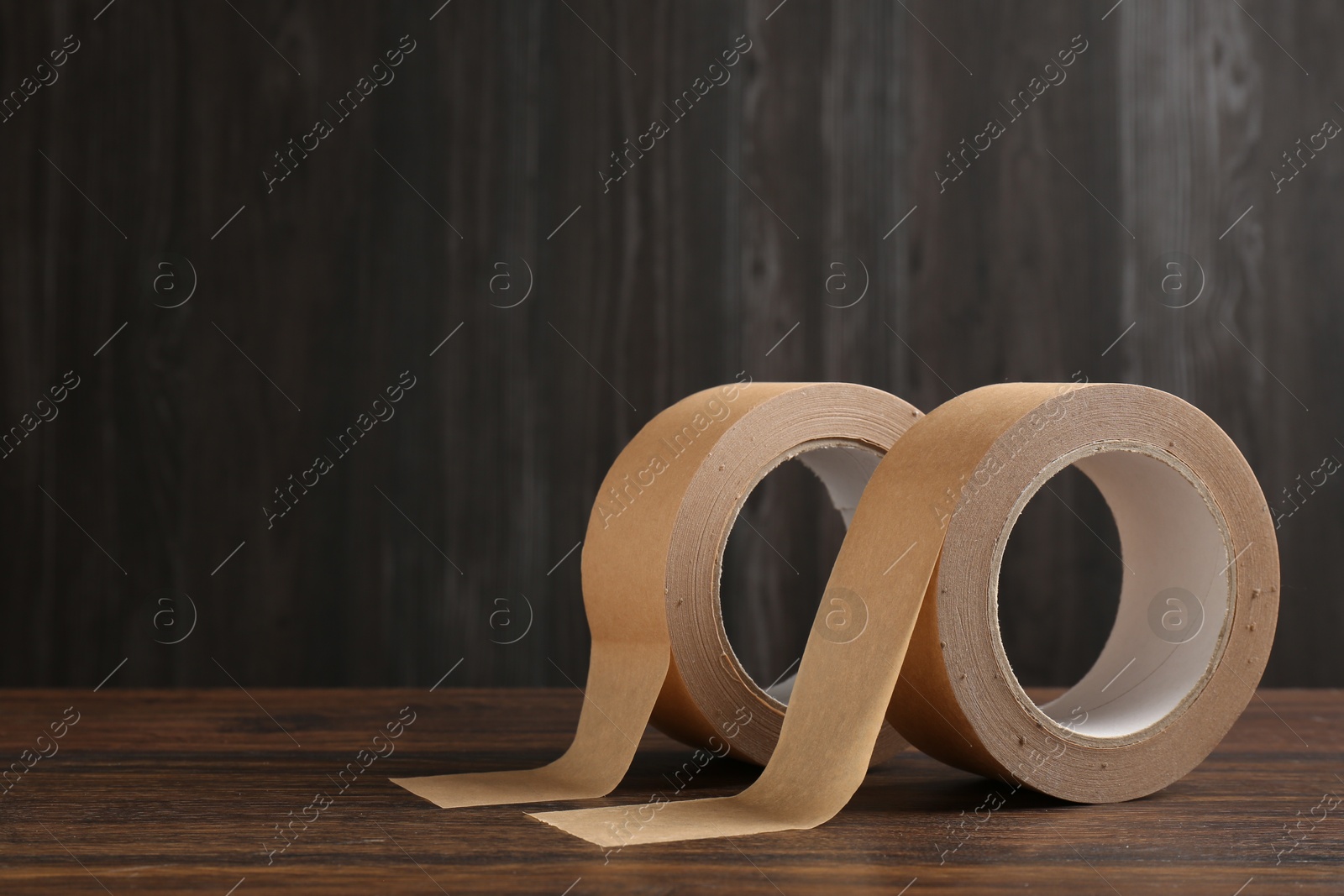 Photo of Two masking tapes on wooden table, closeup. Space for text