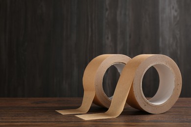 Two masking tapes on wooden table, closeup. Space for text