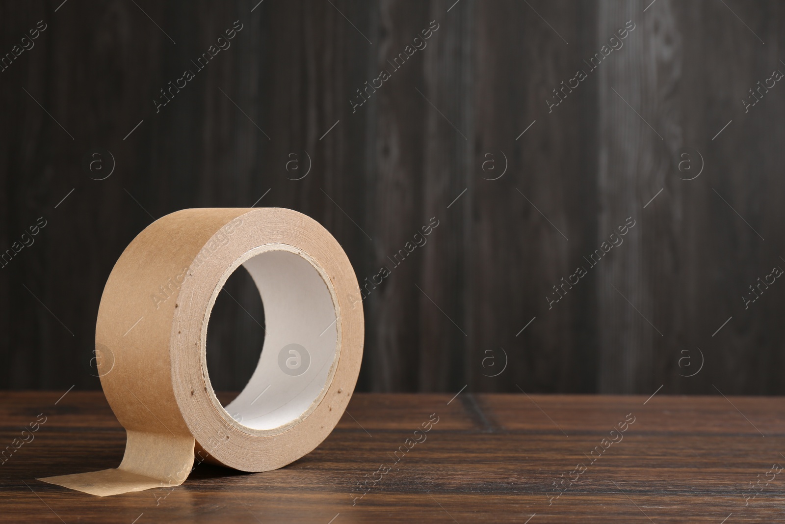 Photo of One masking tape on wooden table, closeup. Space for text