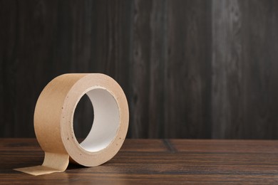 Photo of One masking tape on wooden table, closeup. Space for text