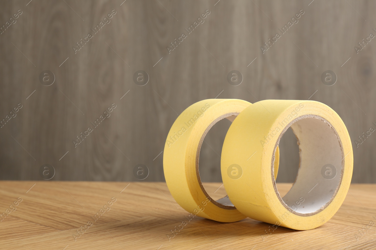 Photo of Two masking tapes on wooden table, closeup. Space for text