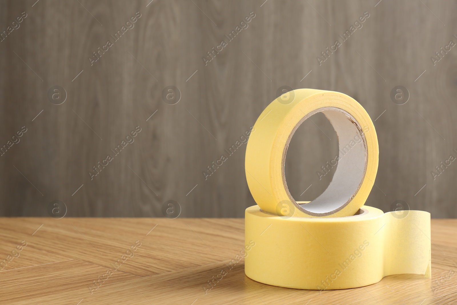 Photo of Two masking tapes on wooden table, closeup. Space for text