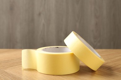 Photo of Two masking tapes on wooden table, closeup