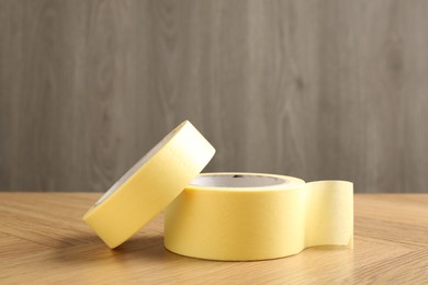 Photo of Two masking tapes on wooden table, closeup