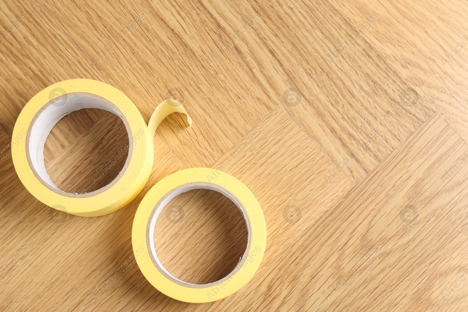 Photo of Two masking tapes on wooden table, top view. Space for text