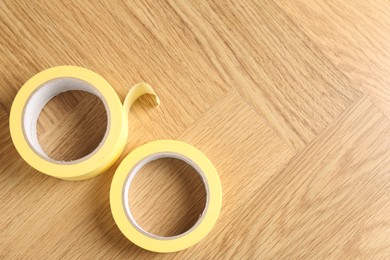 Photo of Two masking tapes on wooden table, top view. Space for text