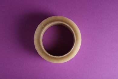 Photo of Roll of masking tape on violet background, top view