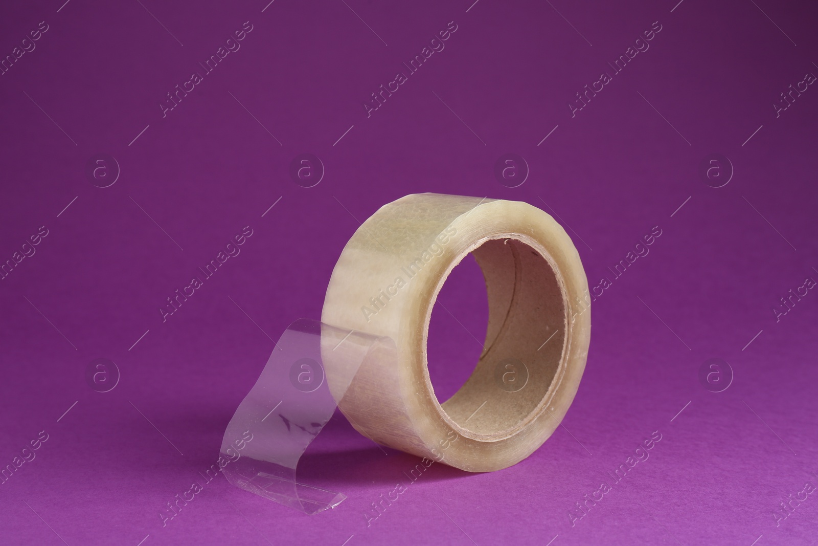 Photo of Roll of adhesive tape on violet background