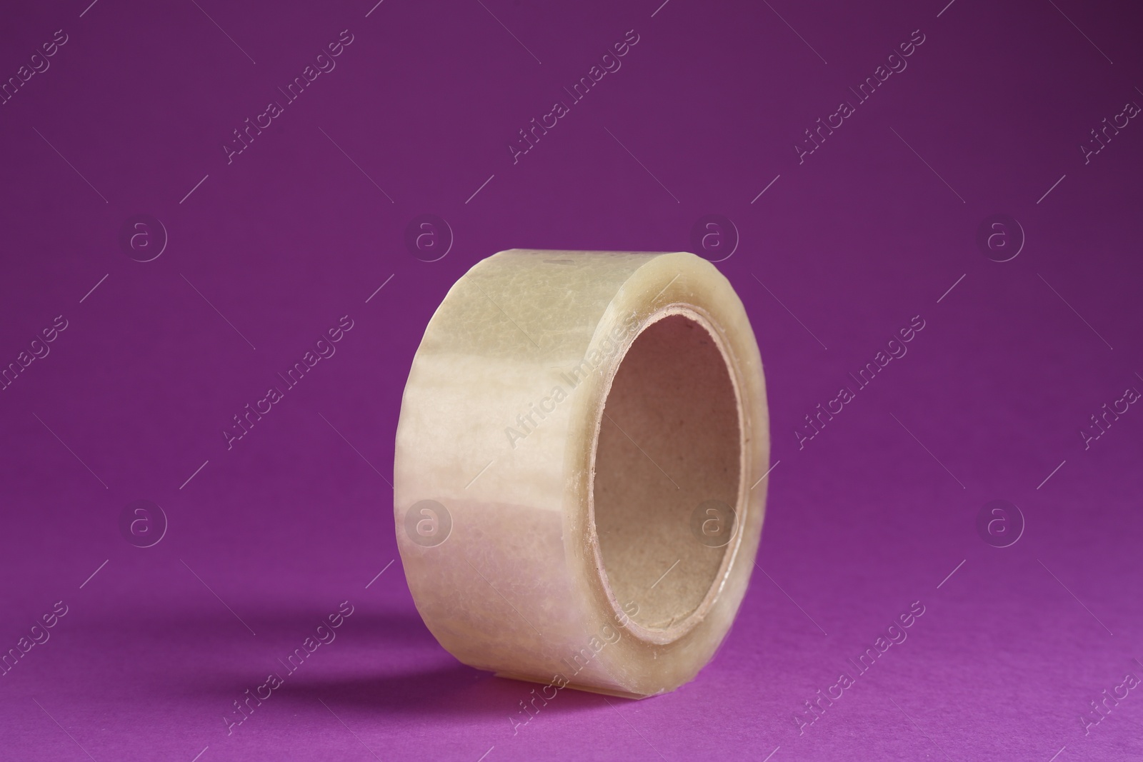 Photo of Roll of adhesive tape on violet background