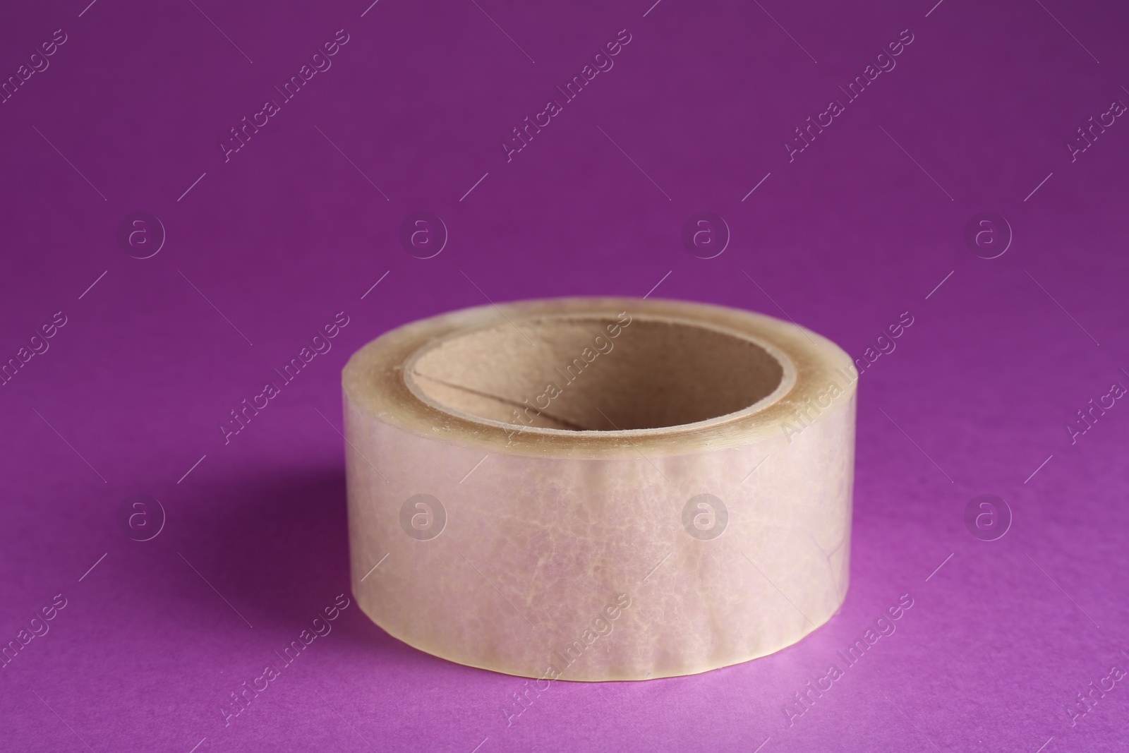 Photo of Roll of adhesive tape on violet background