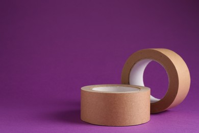 Photo of Rolls of masking tapes on violet background, space for text