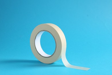 Photo of Roll of masking tape on light blue background