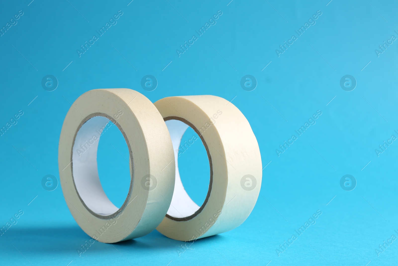 Photo of Rolls of masking tapes on light blue background, space for text