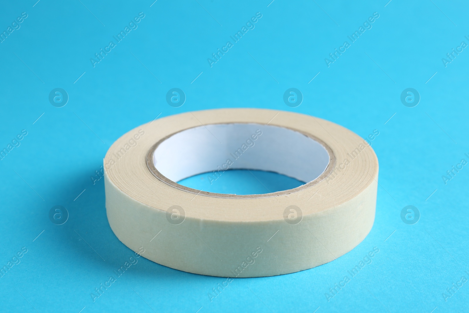 Photo of Roll of masking tape on light blue background