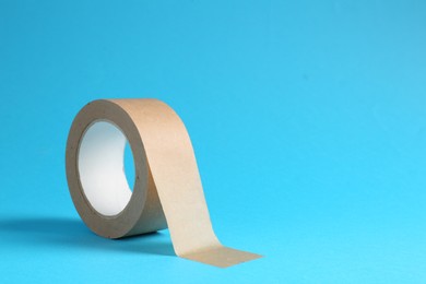 Photo of Roll of masking tape on light blue background, space for text