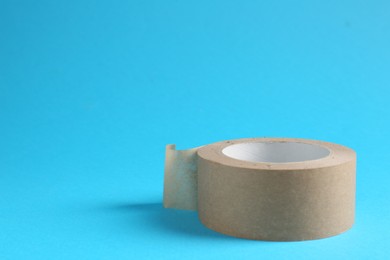 Photo of Roll of masking tape on light blue background, space for text