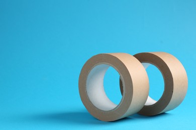 Photo of Rolls of masking tapes on light blue background, space for text