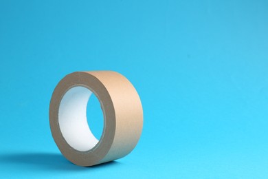 Photo of Roll of masking tape on light blue background, space for text