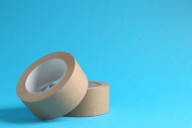 Photo of Rolls of masking tapes on light blue background, space for text