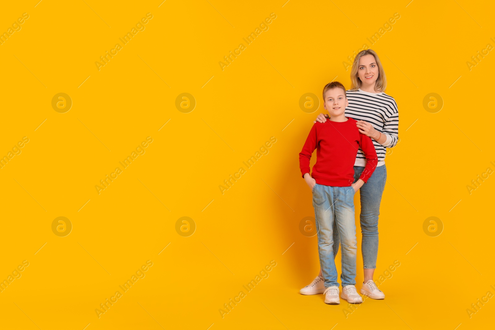 Photo of Happy mother and son on orange background. Space for text