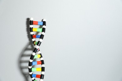 Photo of DNA structure model on light grey background, space for text