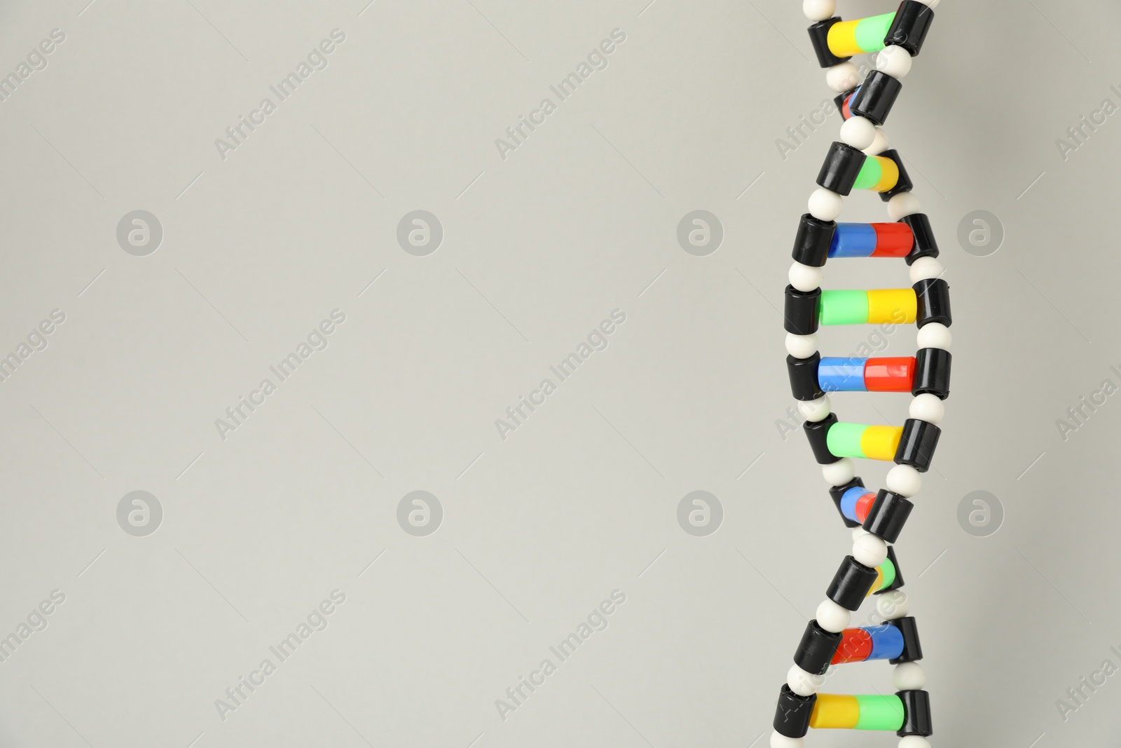 Photo of DNA structure model on light grey background, space for text