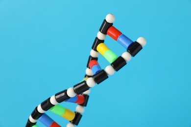 Photo of DNA structure model on light blue background, closeup