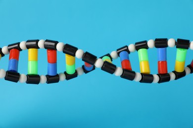 Photo of DNA structure model on light blue background, closeup