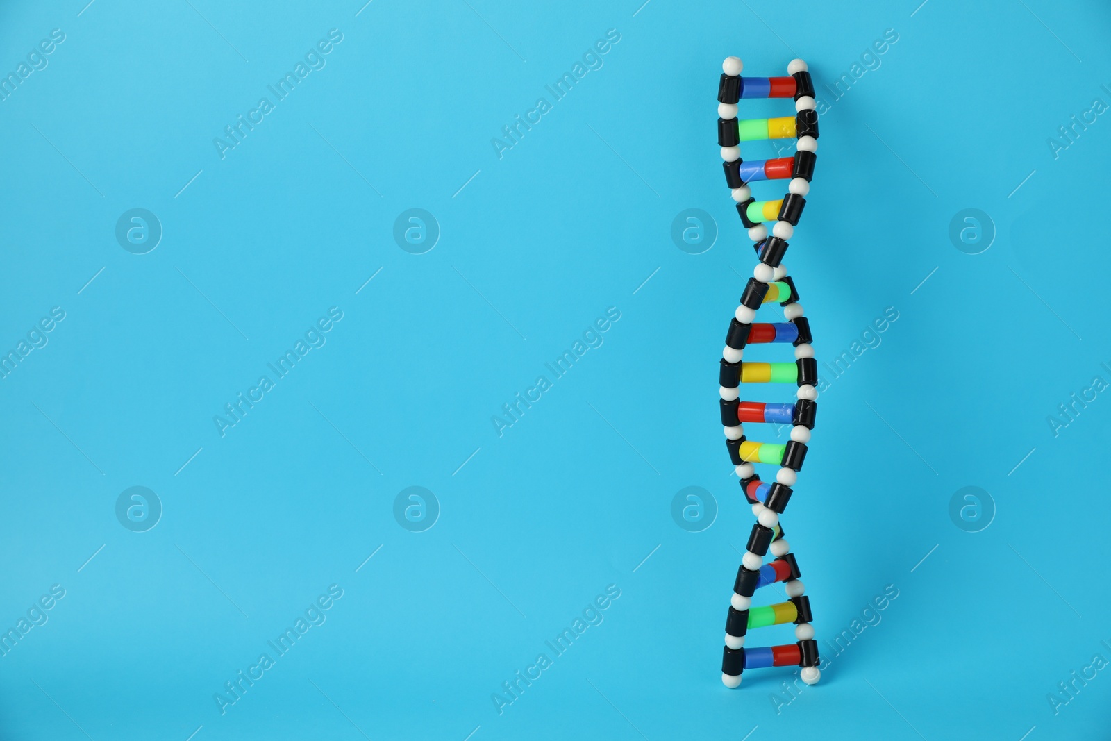 Photo of DNA structure model on light blue background, space for text