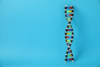 Photo of DNA structure model on light blue background, space for text